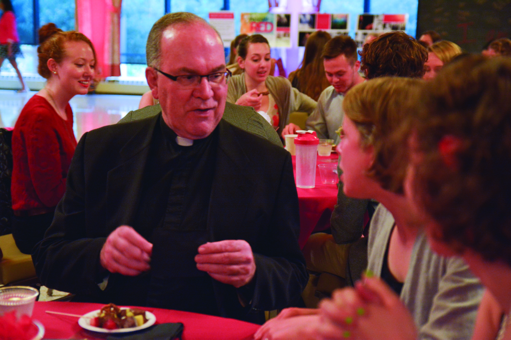Father Steve Sunbourg sits and chats with students at the Red Night Out event.