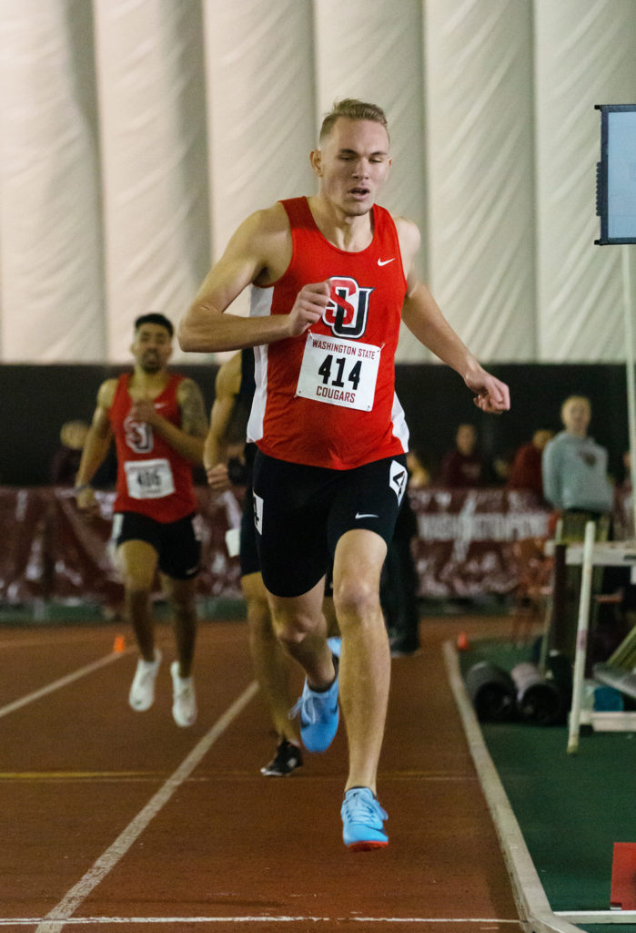 Lucas Milne runs through the finish line as he completes a long distance race at the University of Washington Track.