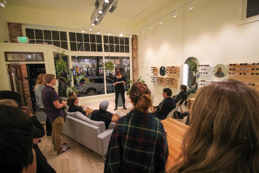 A crowd of onlookers listens to Jessica Mooney as she reads from her book, Parting Gifts for Losing Contestants.”