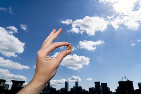 A penny held over the Seattle skyline.