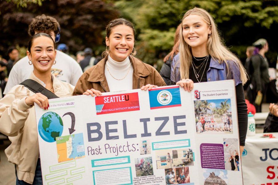 Professionals without borders club members holding a sign describing past projects in Belize.