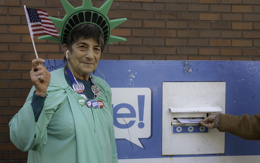 Patti Gorman, waving a miniature American flag and dressed as the Statue of Liberty, urges Seattleites to get their ballots in on time. 