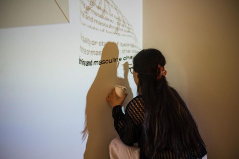 Kira Daley paints a part of Michael Elizabeth’s display for the 2023 Bachelor of Fine Arts show at Seattle U.