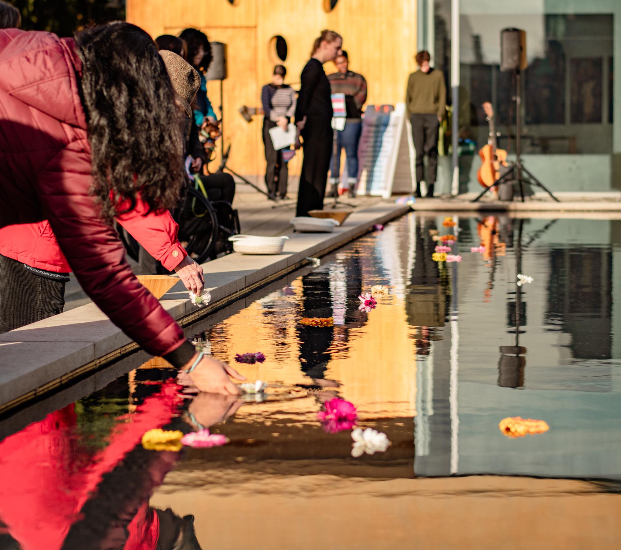 SU community placing flowers in the Reflection Pool during the Transgender Day of Remembrance Vigil.