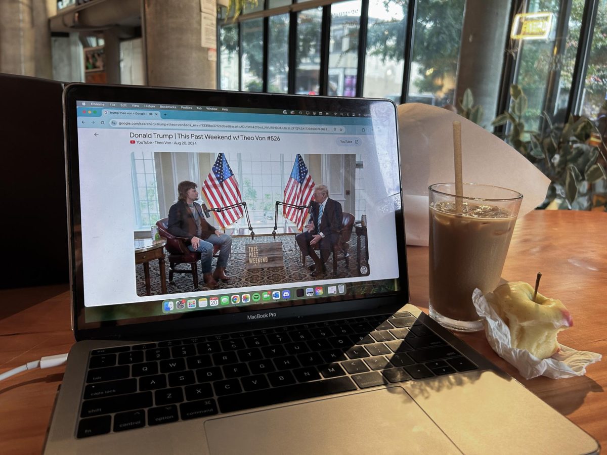 Laptop at a coffee shop displaying Theo Von’s viral podcast episode that features Donald Trump.