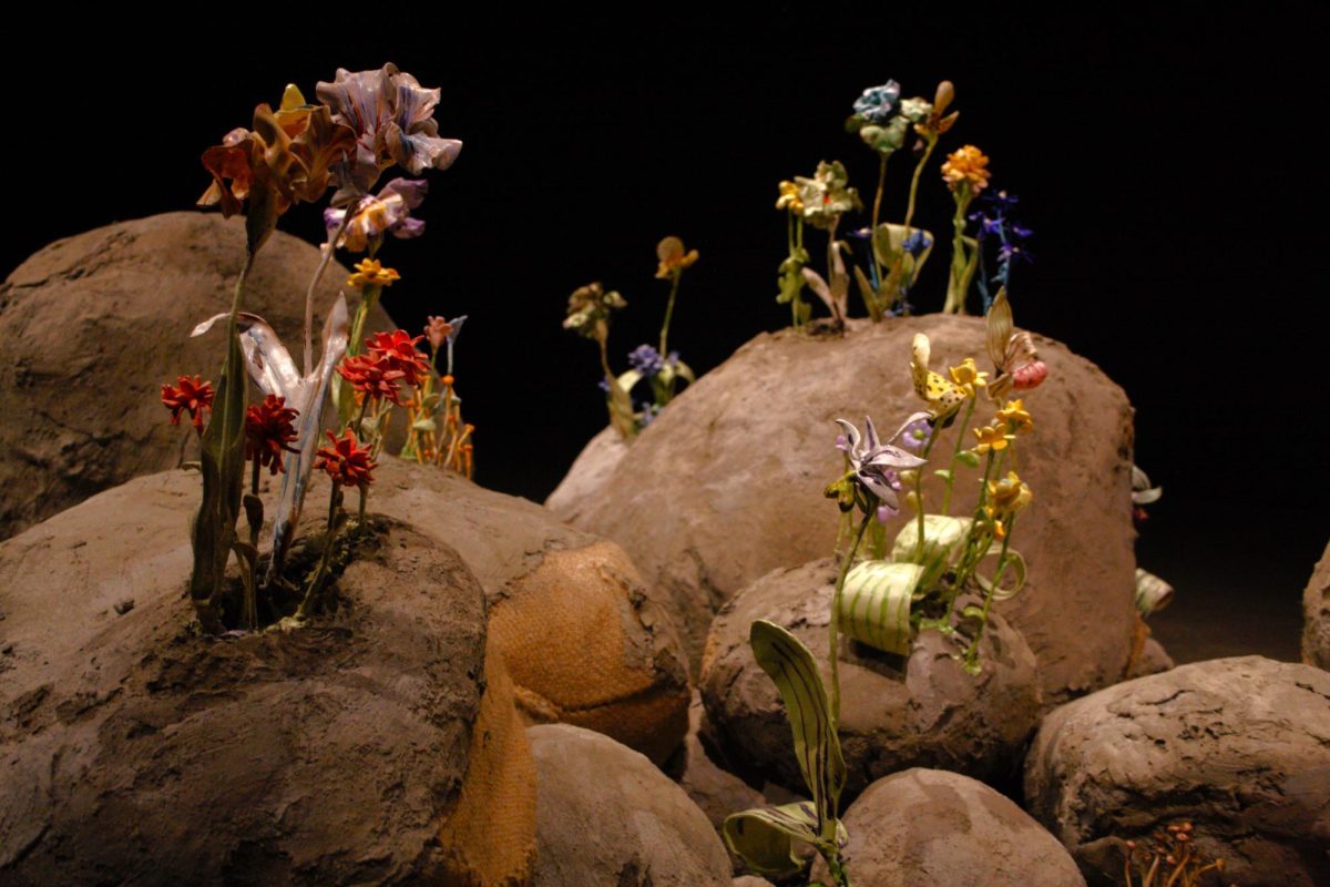 Glazed clay and glass flowers, sprouting from large man-made rocks.