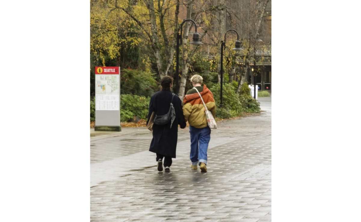 Two students walk through campus hand in hand.