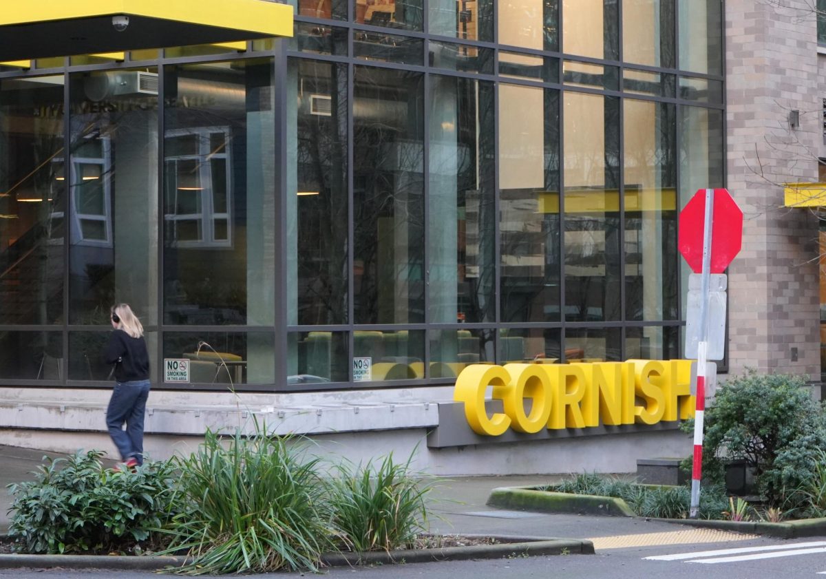 A pedestrian walks in front of the Cornish sign.