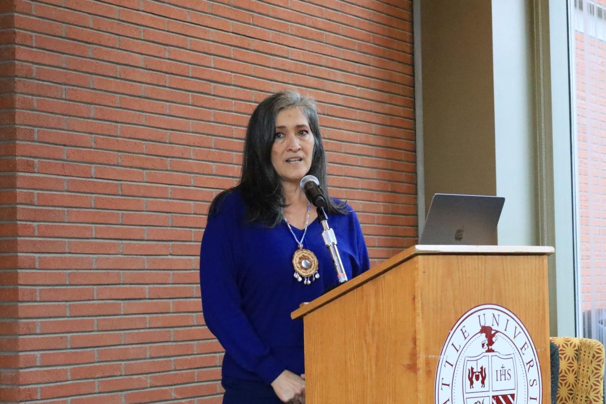 Vi “taqʷšəblu” Hilbert’s daughter, Jill “tsi sqʷux̌ʷaʔł” La Pointe, senior director of Seattle University’s IPI, makes an opening speech introducing author Janet Yoder.