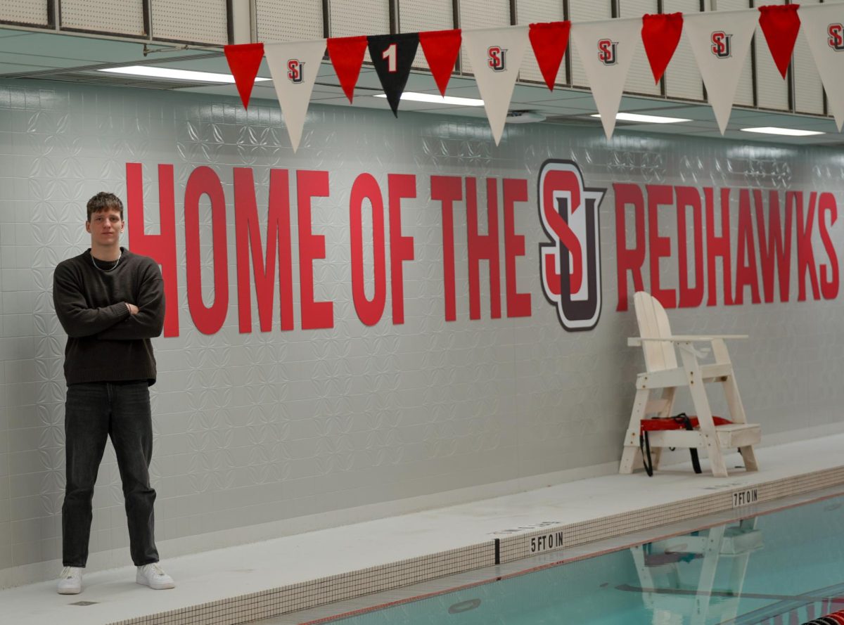 Danielis Kvederis stands next to “Home of the Redhawks” decal by the Seattle U Pool.