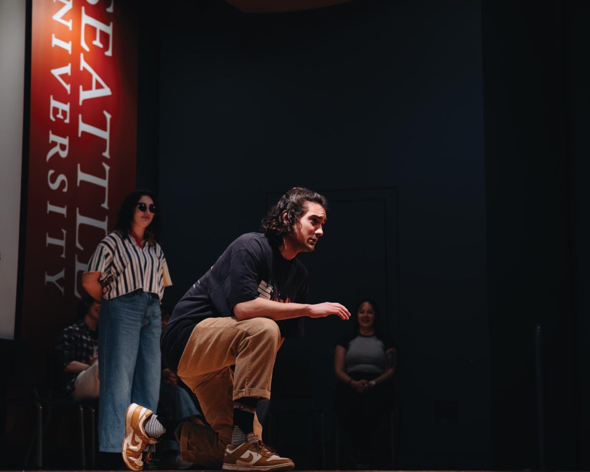 A performer from the Improv team kneels on stage during an improvisational scene