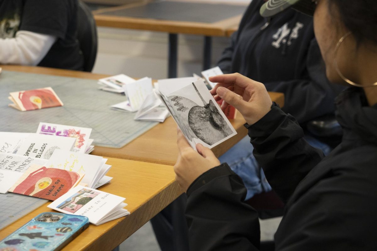 A student in Professor Mouton’s zinemaking class reads Trudy Shelf’s zine titled “Cherry” during a class critique.