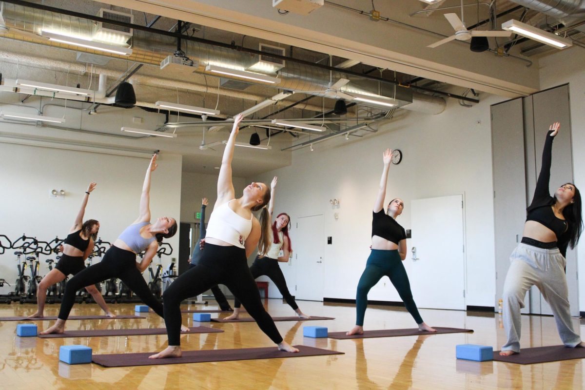 Students raise their hands and heads upward, performing the exalted Crescent Lung Pose.
