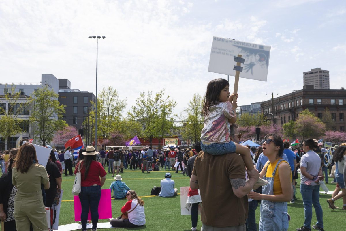 A child holds a picket sign as masses gather.