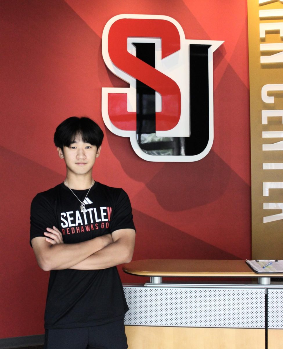 Jacob Kang (‘29) in front of the Seattle University logo.